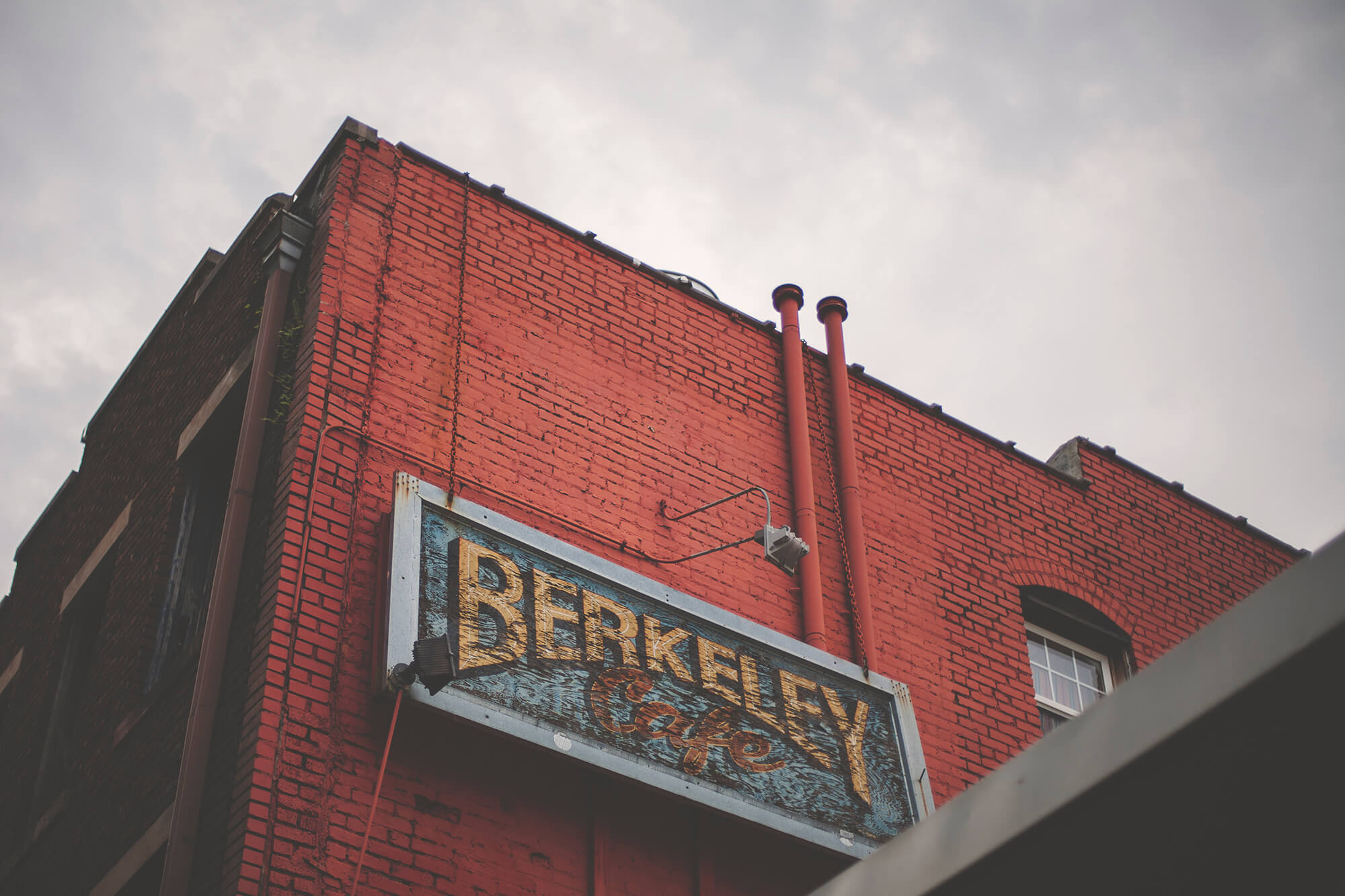 The side of a red brick building with a sign that reads "Berkeley Cafe"