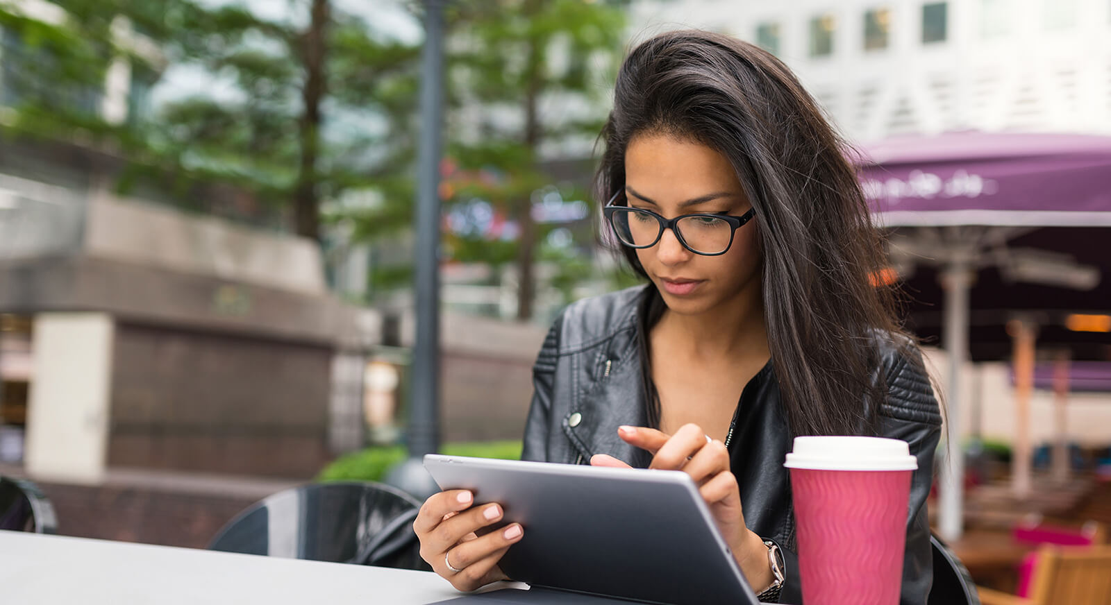 woman using tablet with red coffee cup next to her