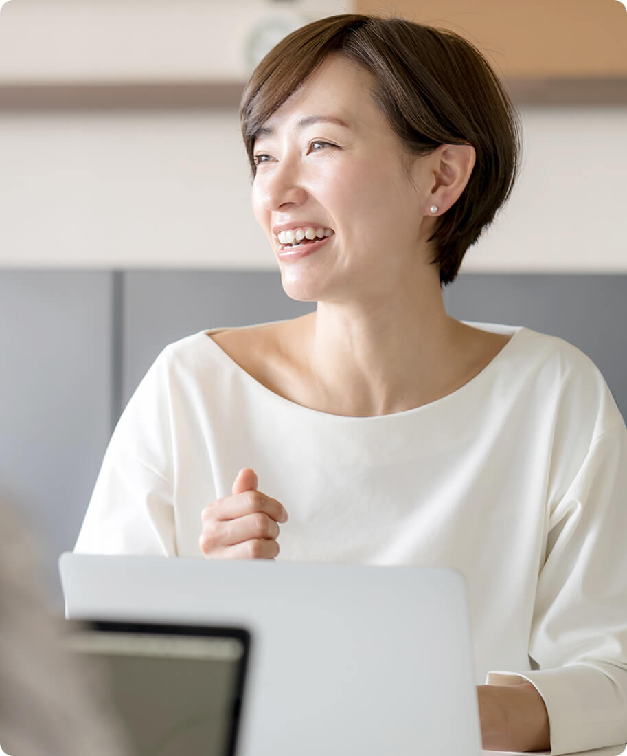 woman in a white shirt sitting behind a laptop