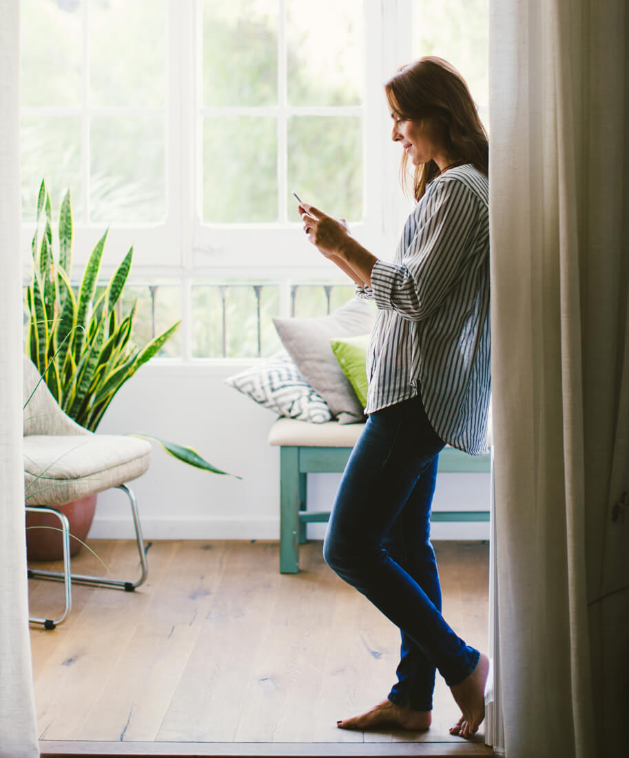 woman leaning against a wall and looking at a phone